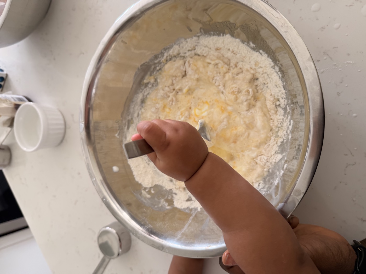 A toddler mixing dough in a bowl during a baking activity
