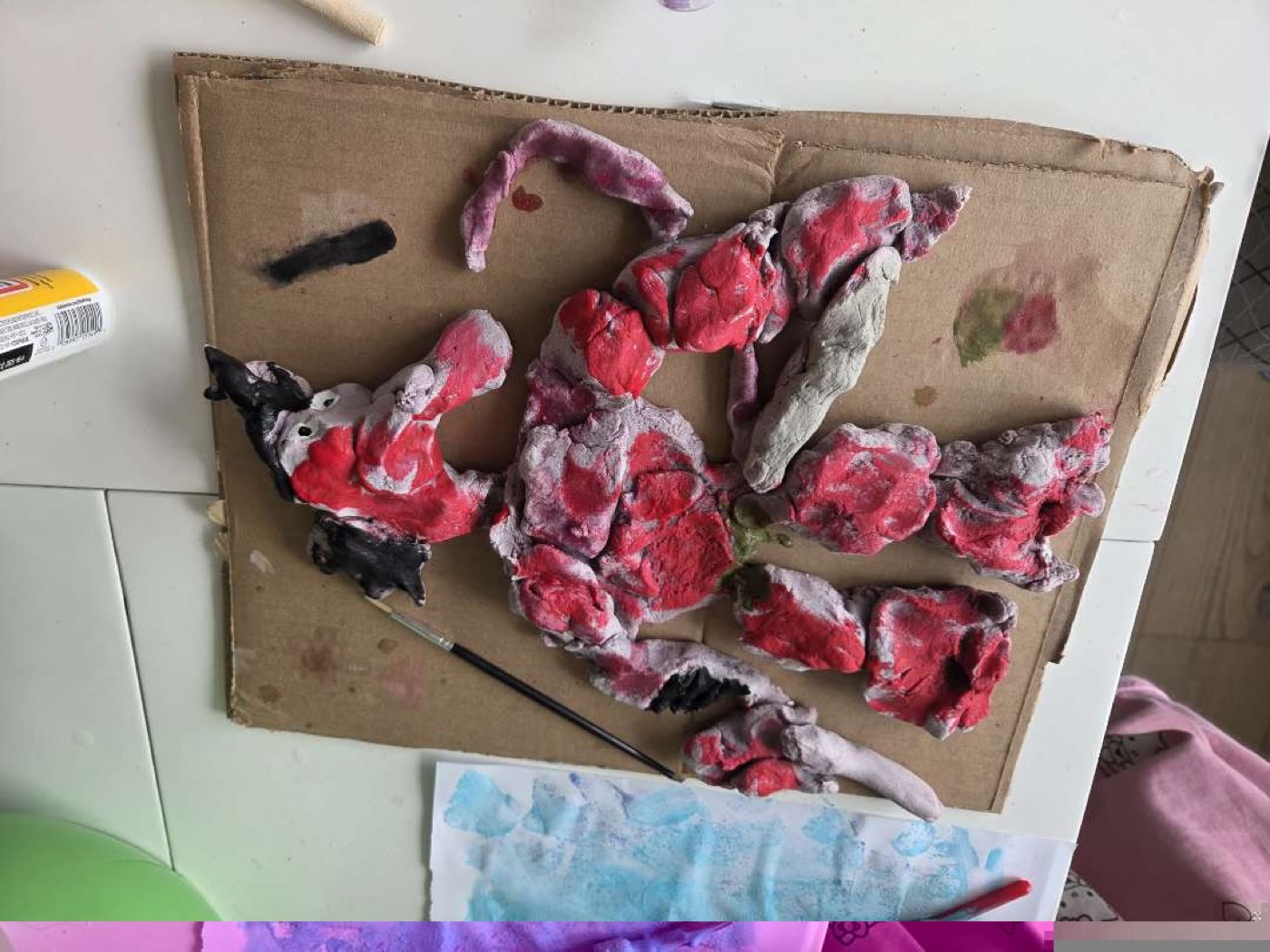 A painted clay figure built on cardboard