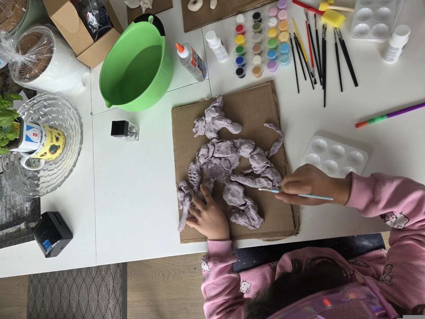A child painting a hand-sculpted clay creation