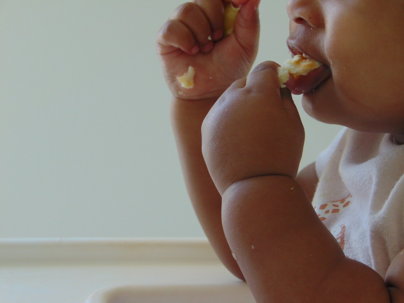 A baby self-feeding a piece of food